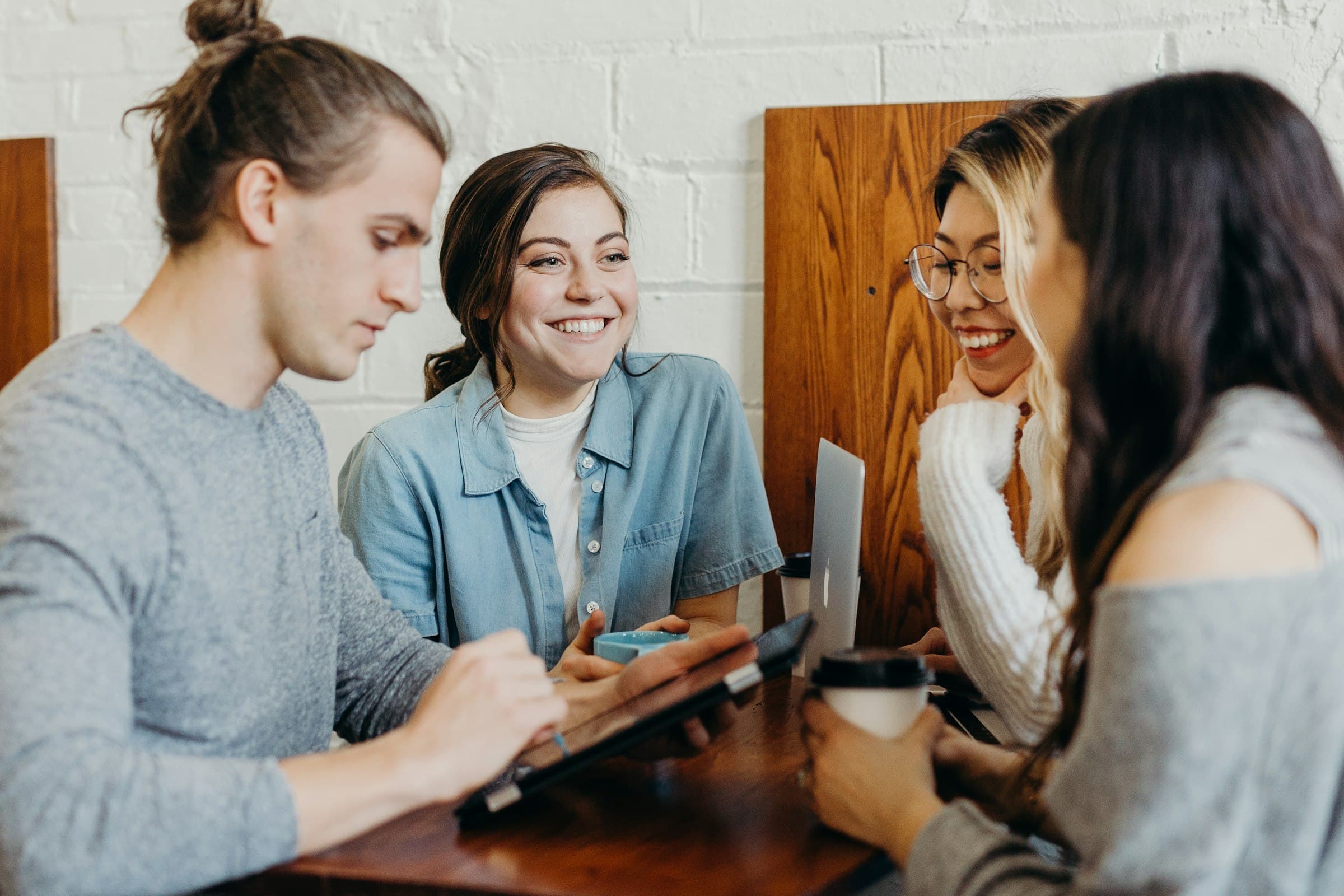 Four colleagues at a cafe table looking up a prior-authorization answer over coffee